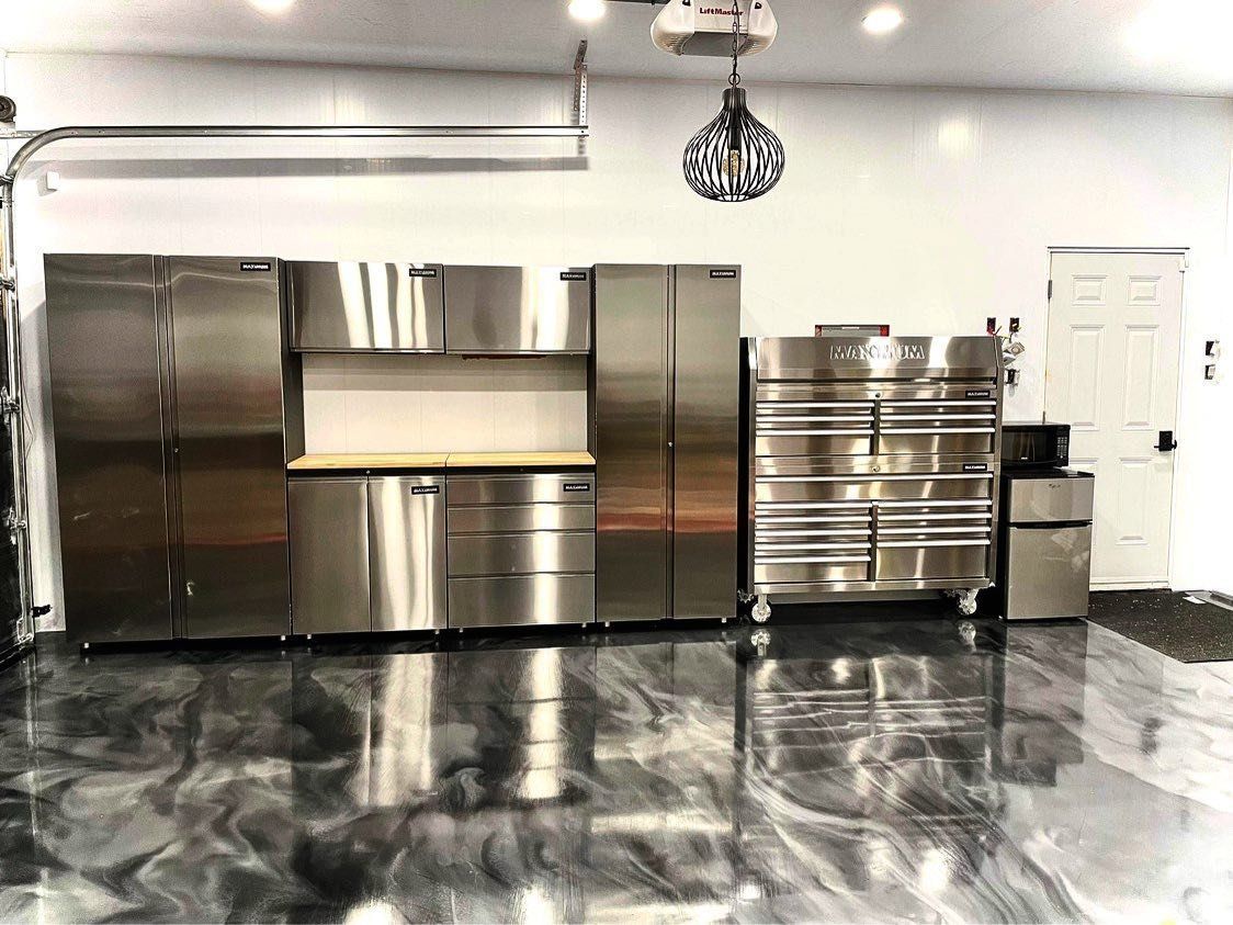 Un garage avec des armoires en acier inoxydable, un réfrigérateur et une boîte à outils.