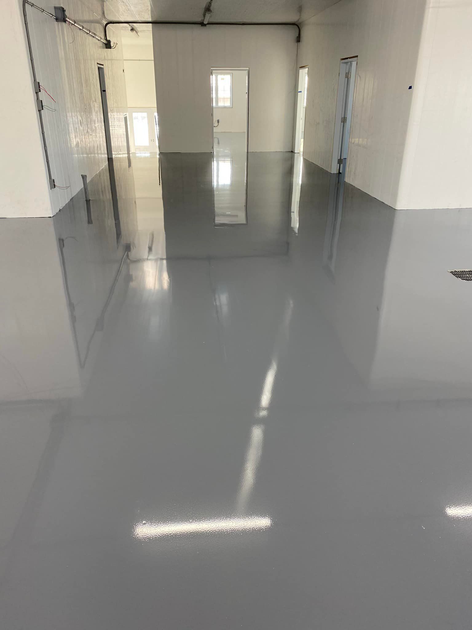 Une grande pièce avec un sol gris et des murs blancs.
