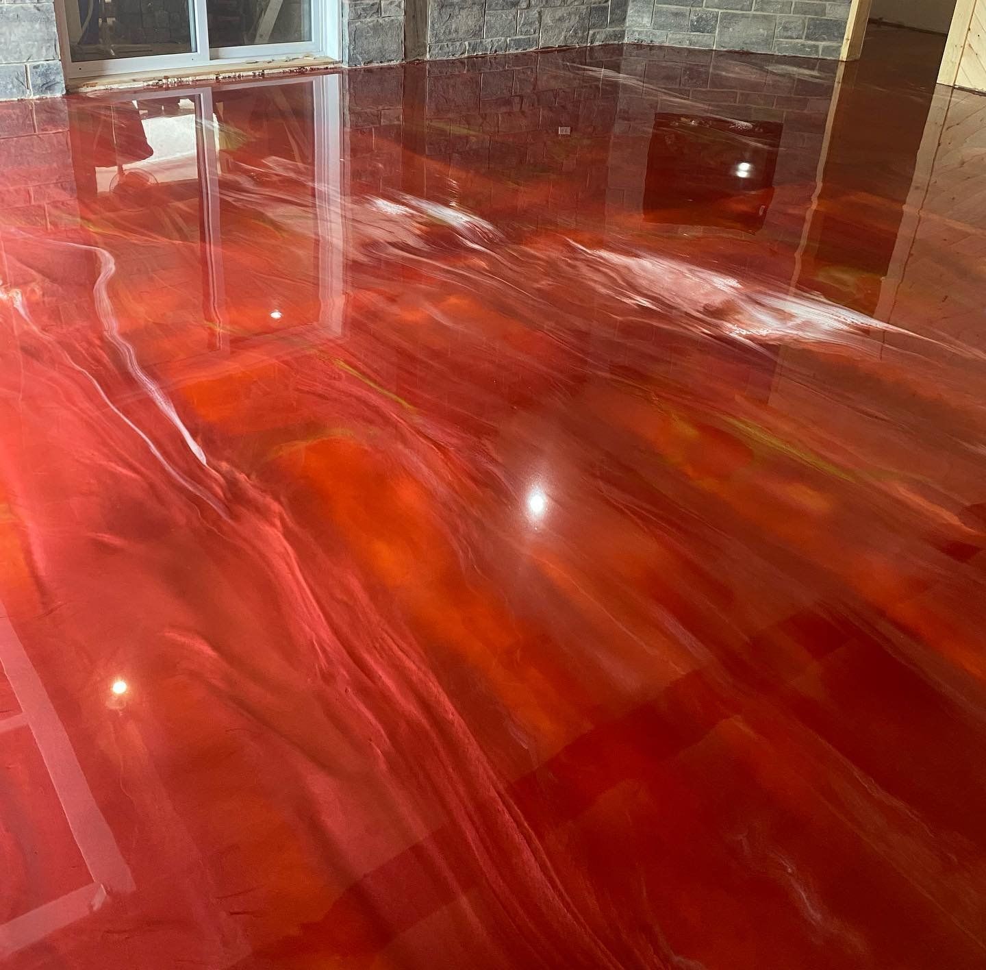 Un sol métallique rouge dans une pièce avec le reflet d'une fenêtre.