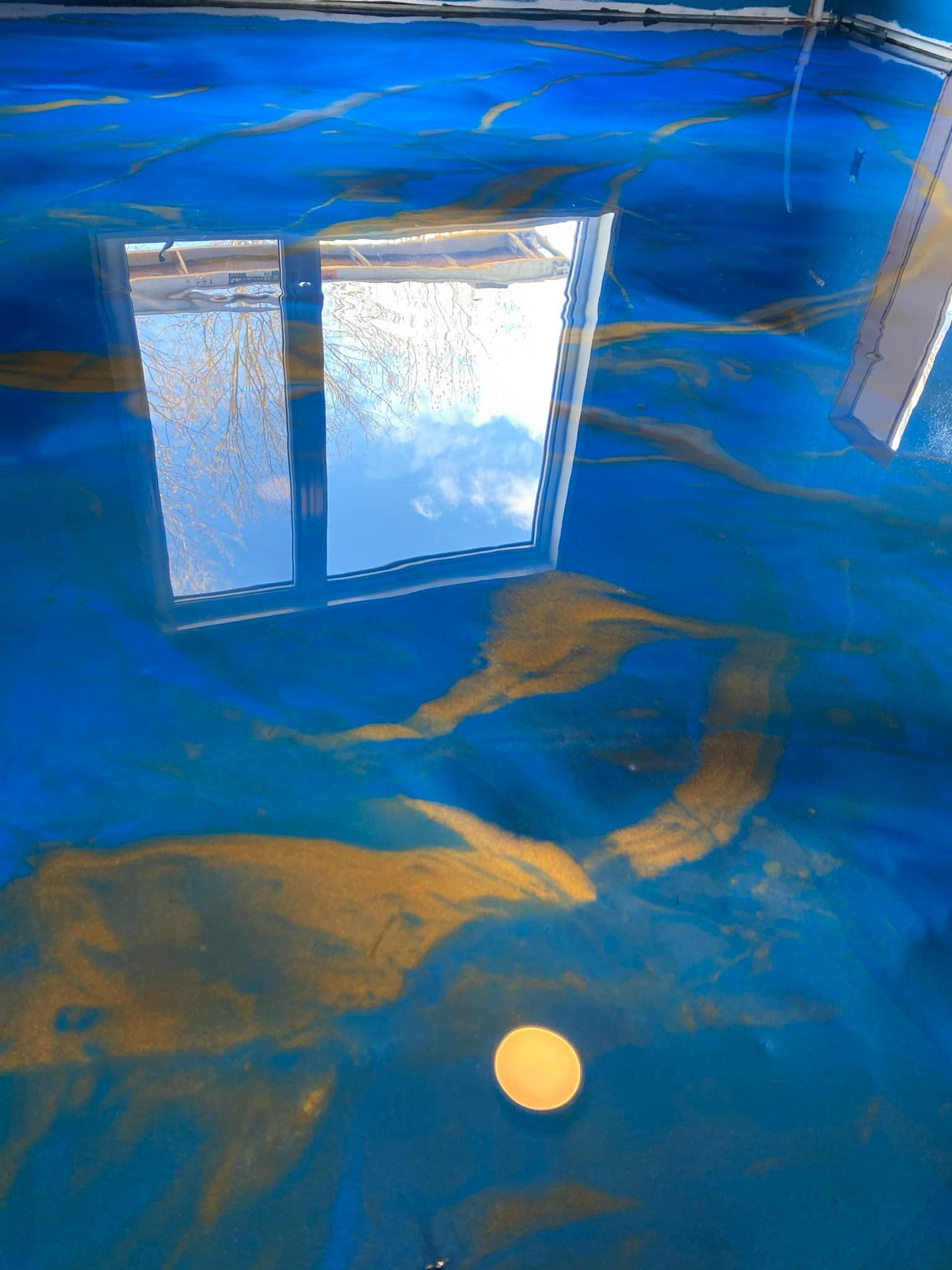 Un sol bleu et or avec une fenêtre qui s'y reflète.