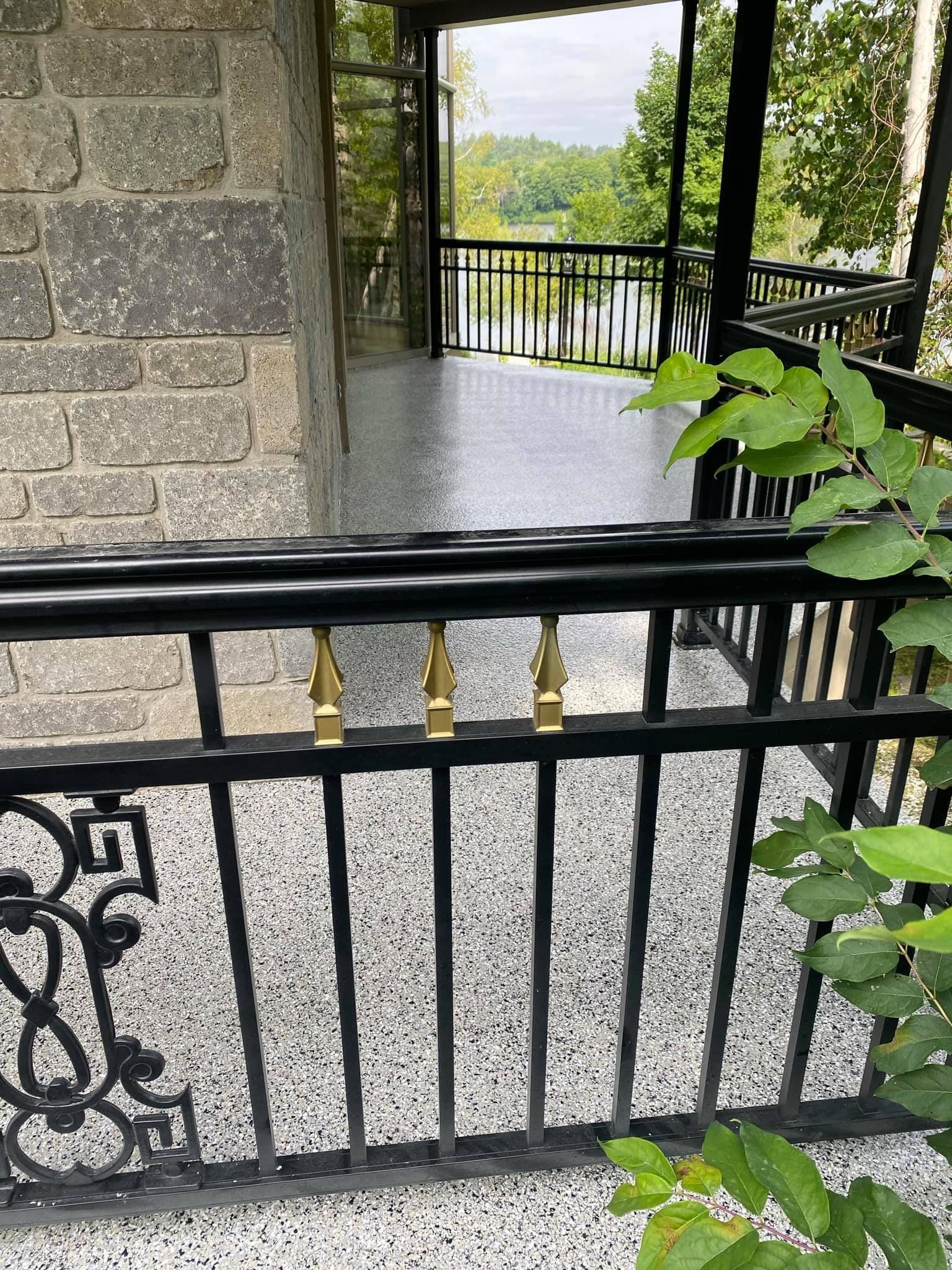 Un balcon avec une balustrade noire et une vue sur un lac.