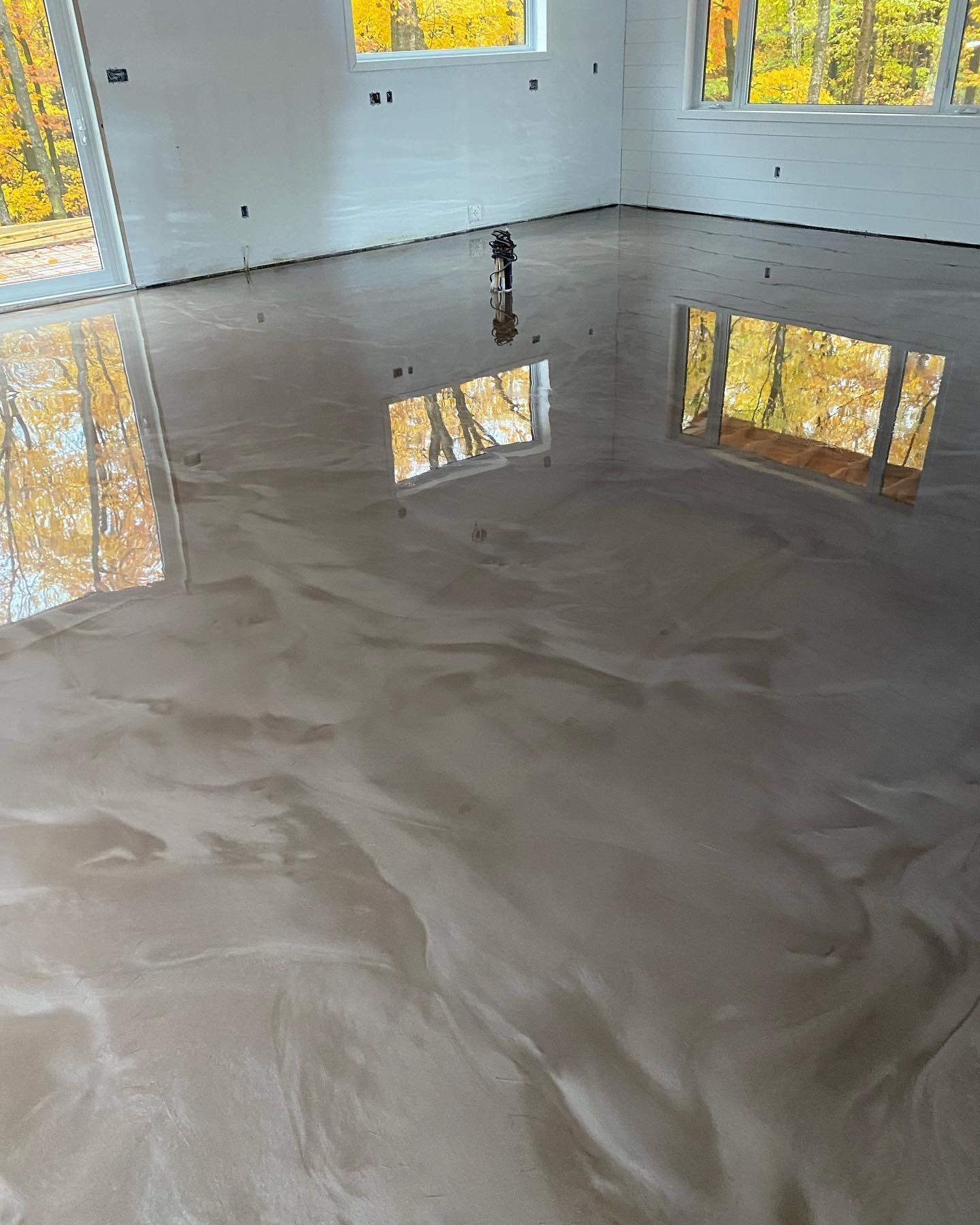 Une pièce avec un sol brillant et un reflet d'arbres dans le sol.