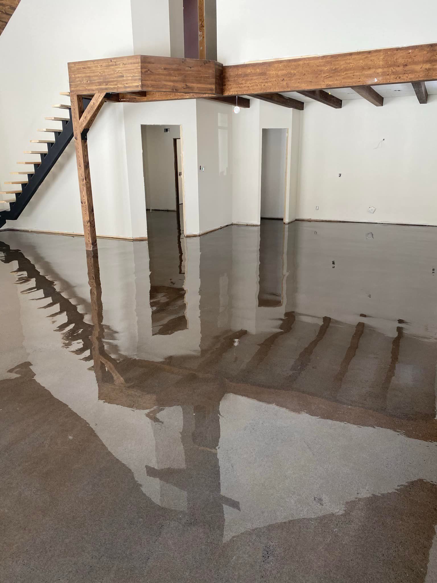 Une pièce avec un escalier et un reflet de l'escalier dans le sol