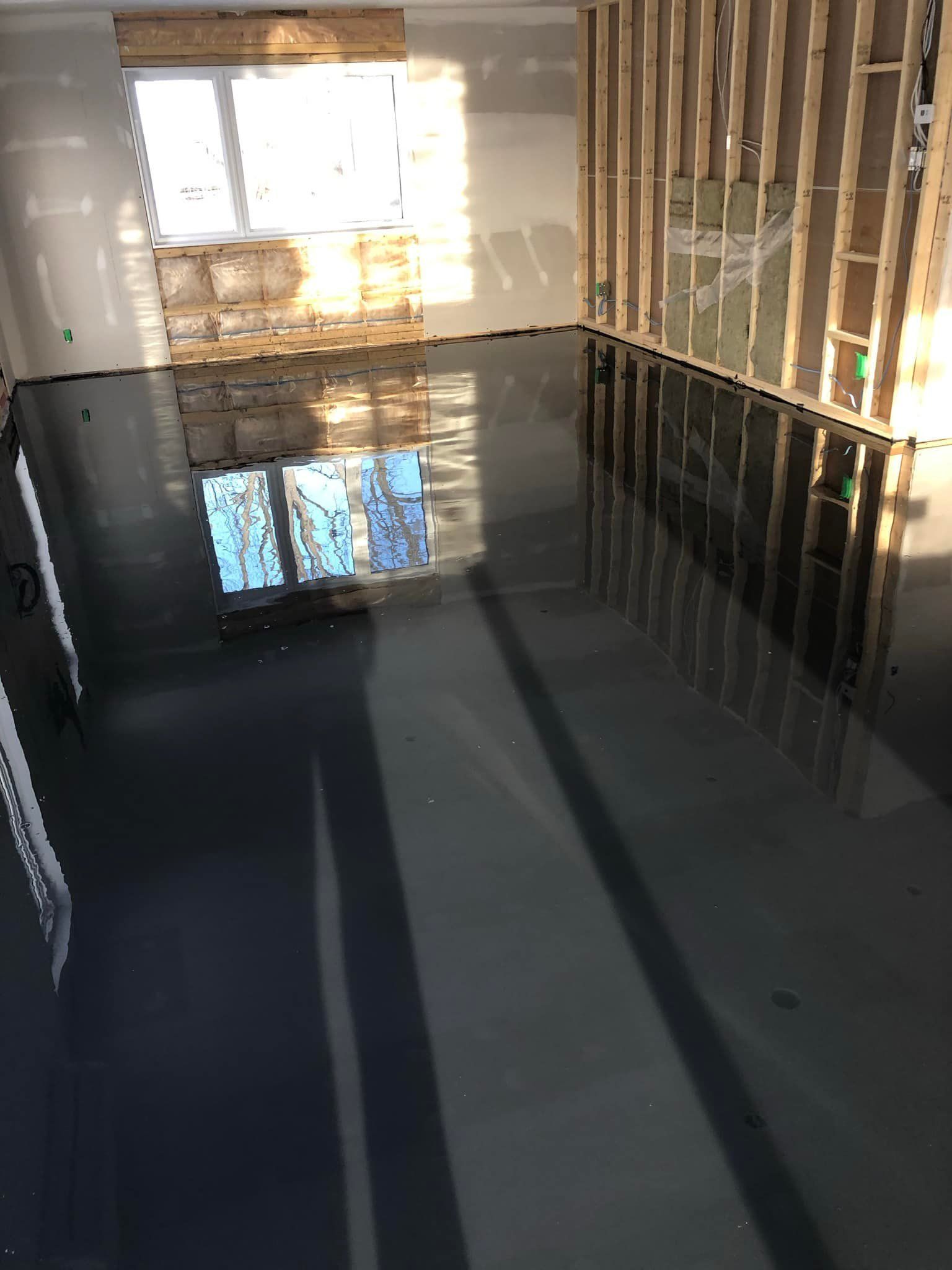 Une pièce avec un sol noir et une fenêtre.