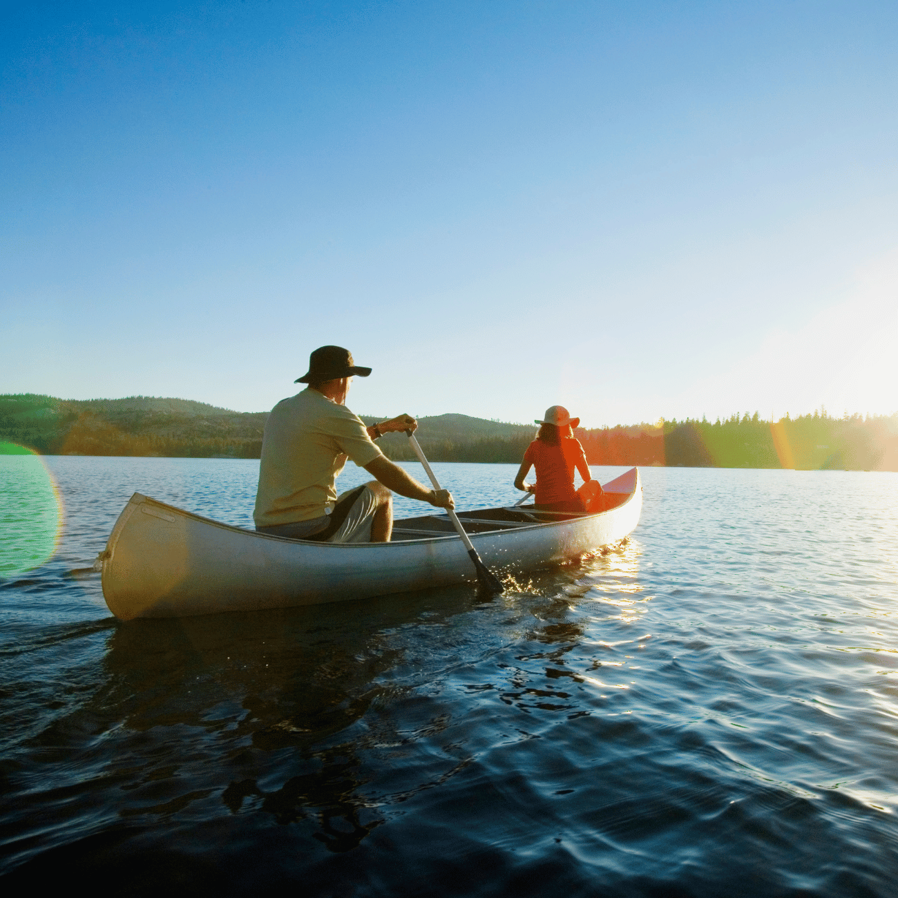 A man and a woman are paddling a canoe on a lake.