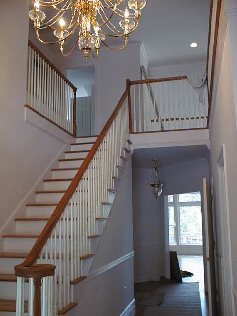 A hallway with stairs and a chandelier hanging from the ceiling