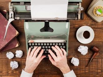 A person is typing on an old typewriter on a wooden table.