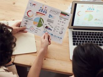 A man and a woman are sitting at a table looking at a graph.