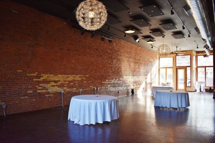 Event space with brick wall, white tables, and large orb light fixtures.