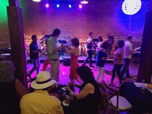 People dancing to live music in a dimly lit venue with brick walls.