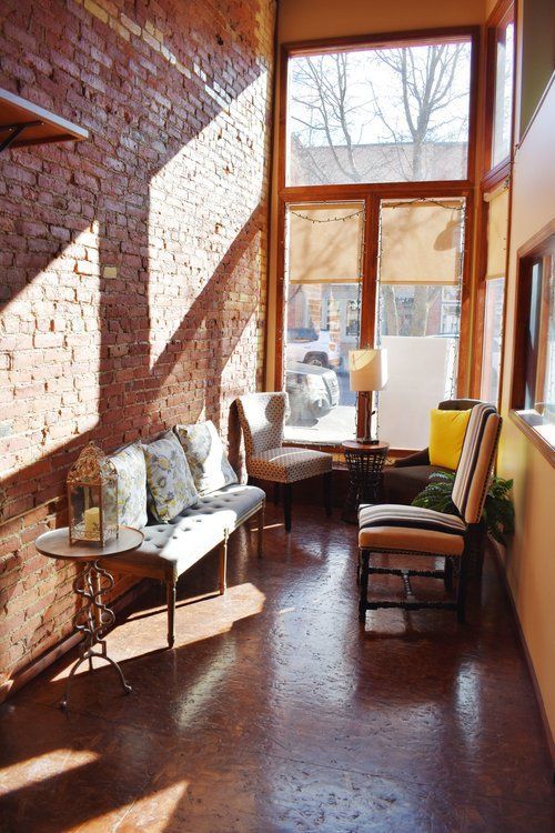 Sunroom with brick wall, seating, and large windows.
