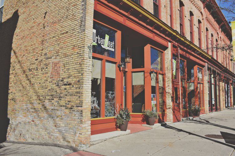 Brick building with red trim, storefront windows, and the name 