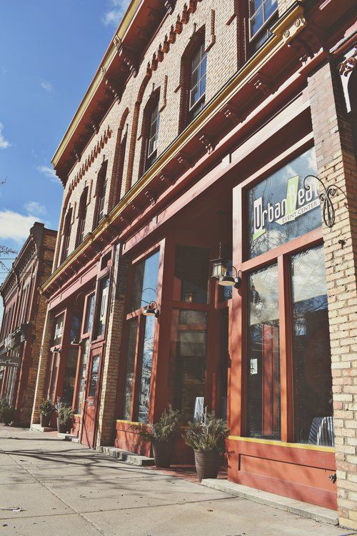 Brick building, Urban Leaf sign above doorway, street view, sunny day.