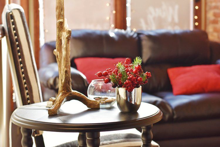 A small black table with a decorative centerpiece in front of a leather sofa and chair.