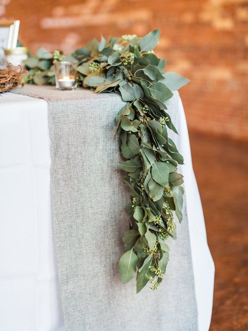 Table set with white tablecloth, gray runner, and eucalyptus garland.