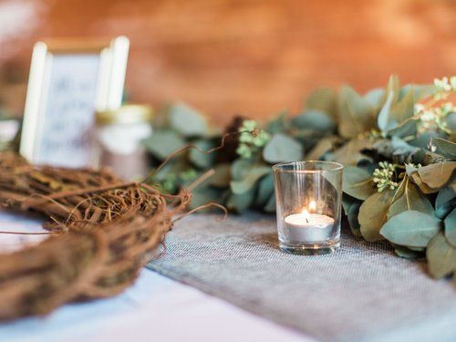Candlelit votive on a gray runner, greenery, and a rustic grapevine wreath.