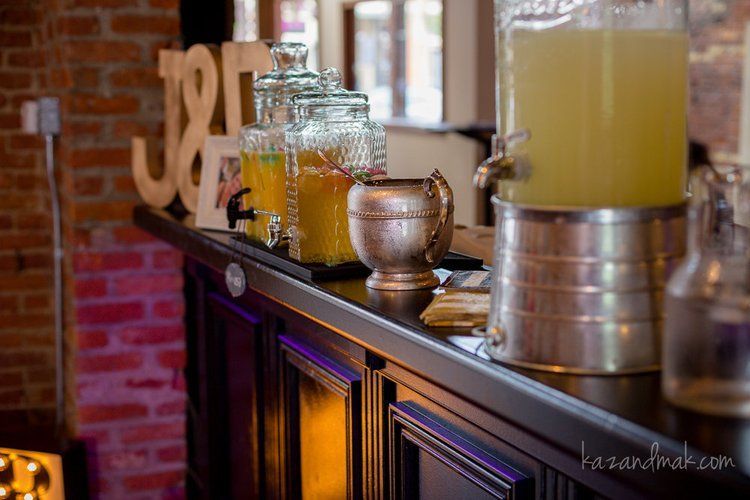Bar with glass beverage dispensers, a metal pitcher, and decorative wooden numbers.