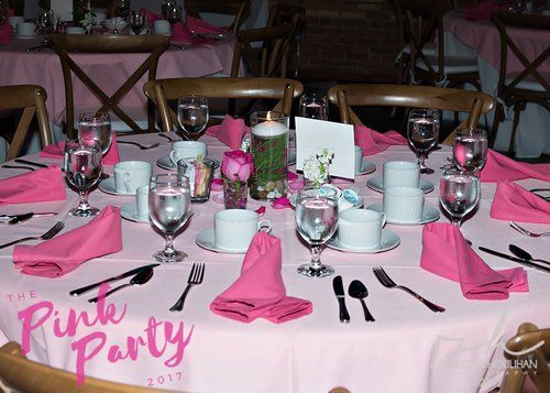 Pink party table setting with napkins, glasses, and silverware.
