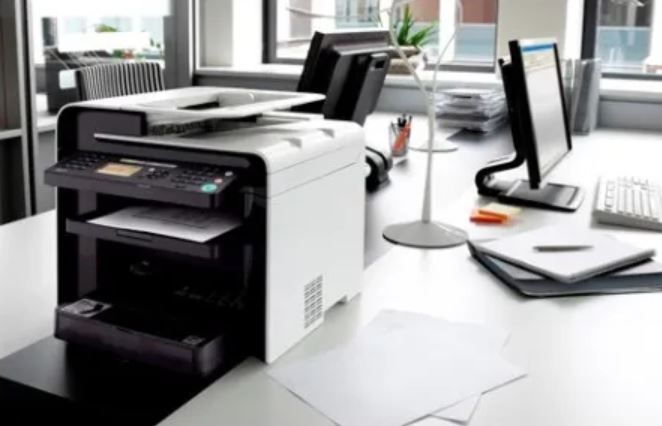 Una impresora láser multifunción en blanco y negro sobre un escritorio de oficina