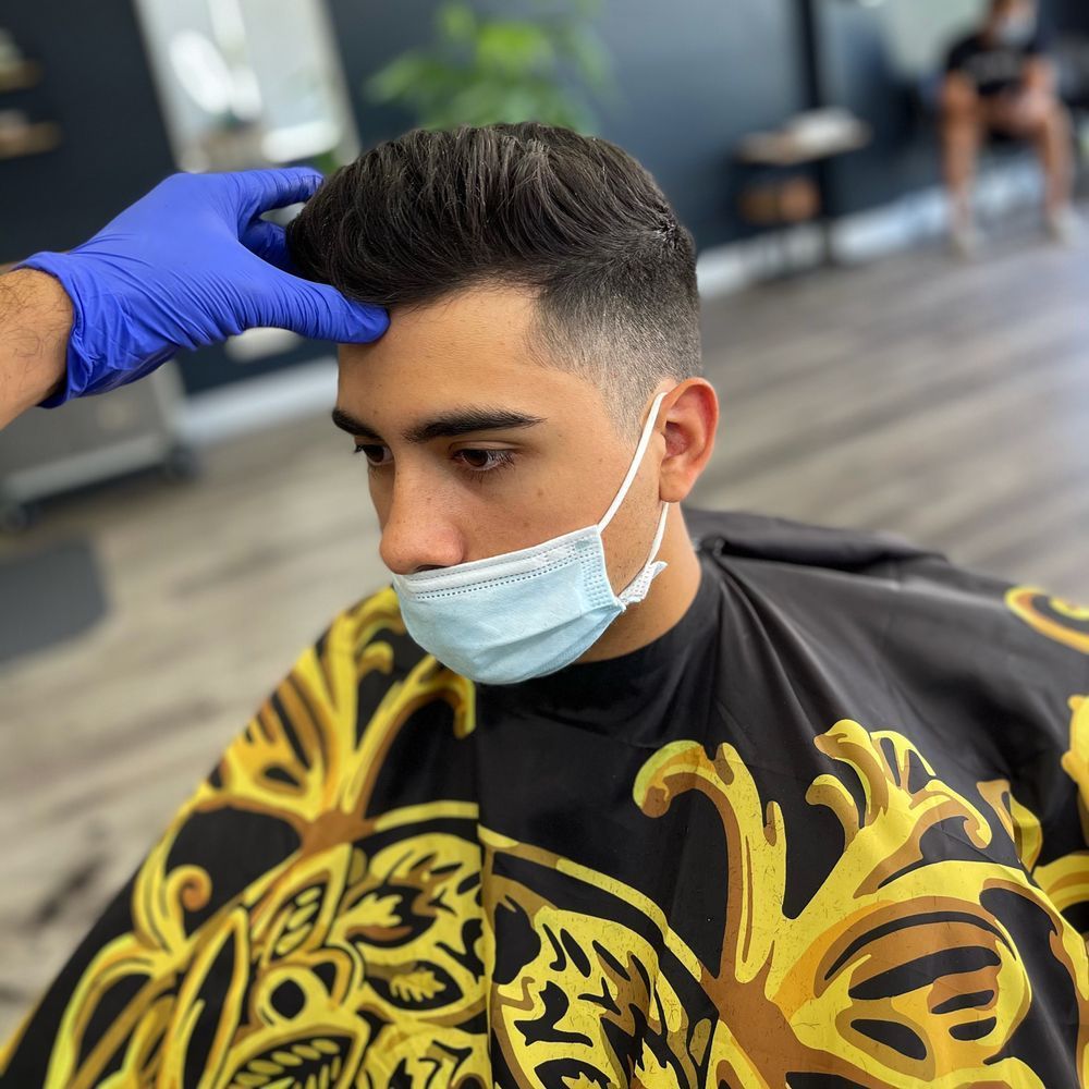 A man wearing a mask is getting his hair cut by a barber