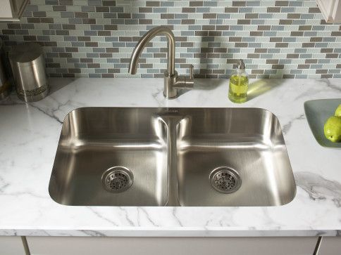 A stainless steel kitchen sink is on a marble counter top.