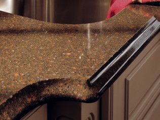 A person is cleaning a kitchen counter with a vacuum cleaner.