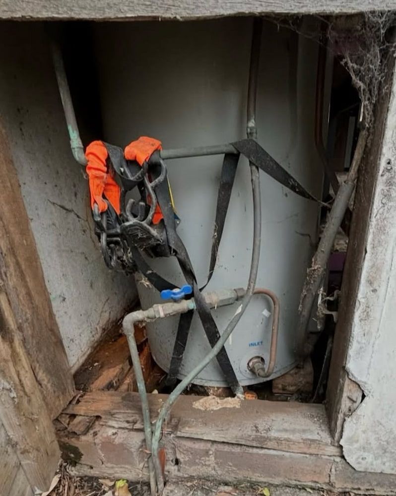 A Grey Water Heater Sits in a Damaged, Unfinished Alcove — Crystal Clear Plumbing & Roofing in Wollongong, NSW