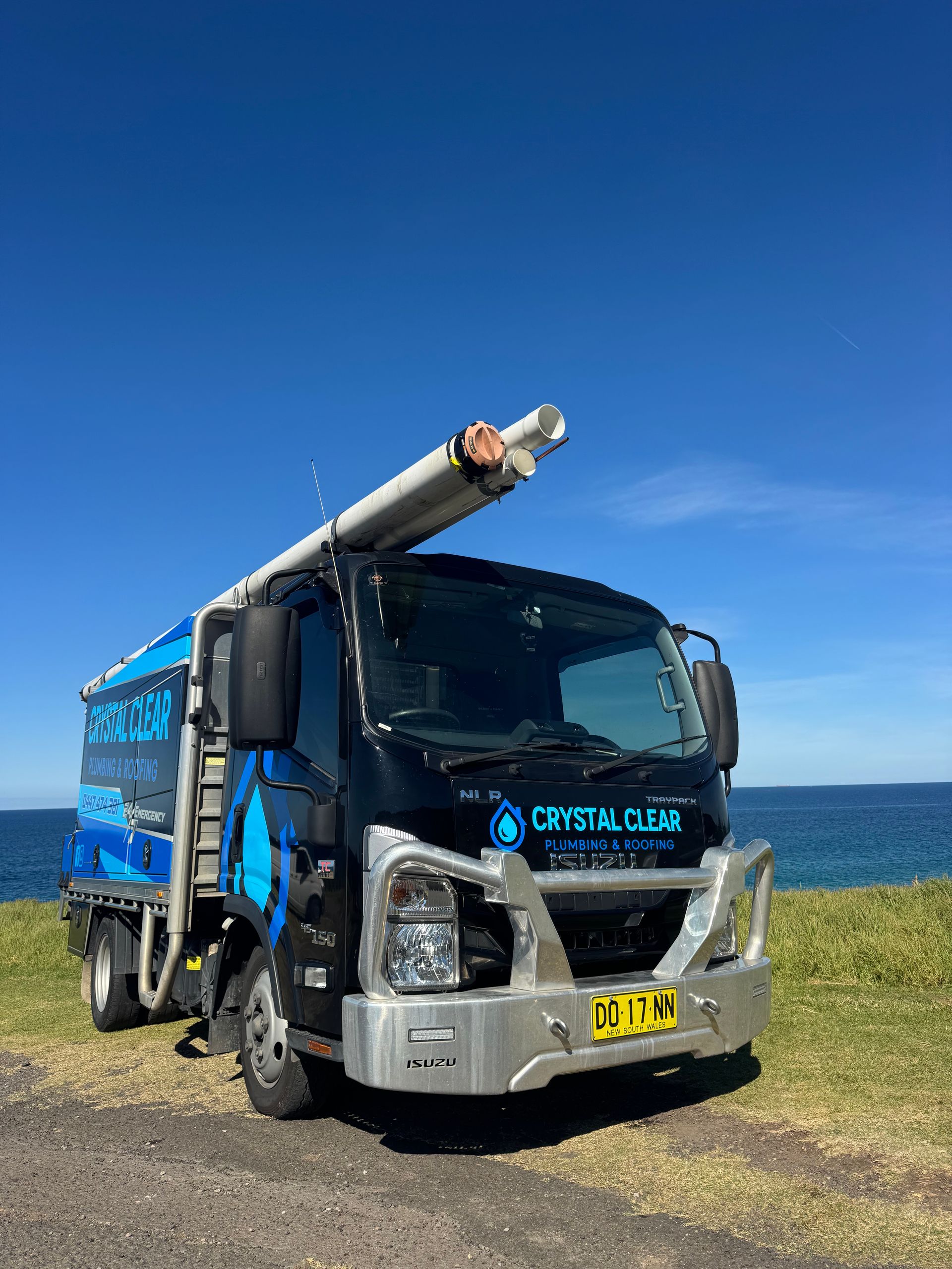 Blue and silver dump truck parked on gravel under a clear blue sky — Crystal Clear Plumbing & Roofing in Wollongong, NSW
