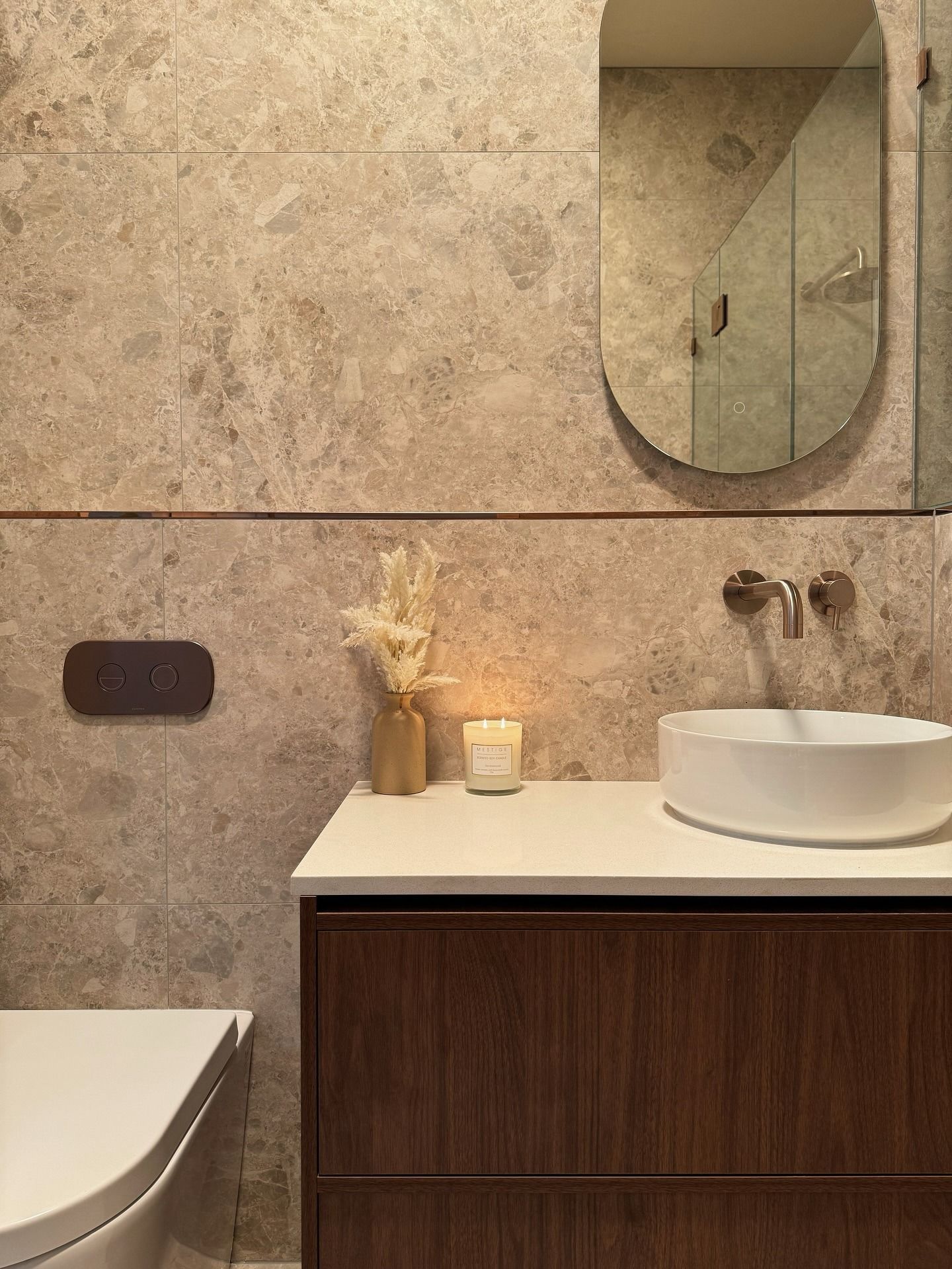 Modern bathroom with beige stone walls, wooden vanity, white vessel sink, and an arched mirror — Crystal Clear Plumbing & Roofing in Wollongong, NSW