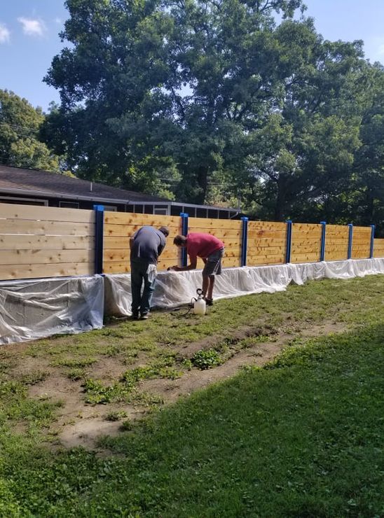 Crew coating a cedar privacy fence