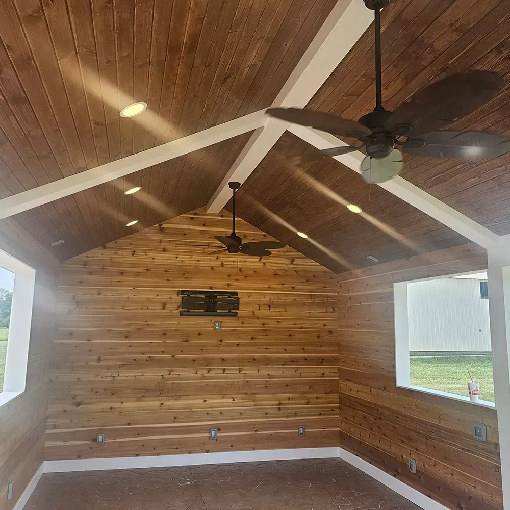 A vaulted room with horizontal cedar wood plank walls and ceiling, white trim, recessed lighting, and two ceiling fans.