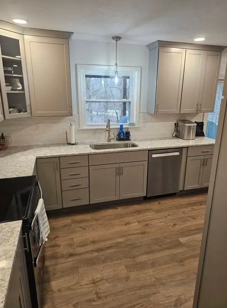 A kitchen featuring light-gray cabinets, granite countertops, stainless steel appliances, and wood-look flooring.