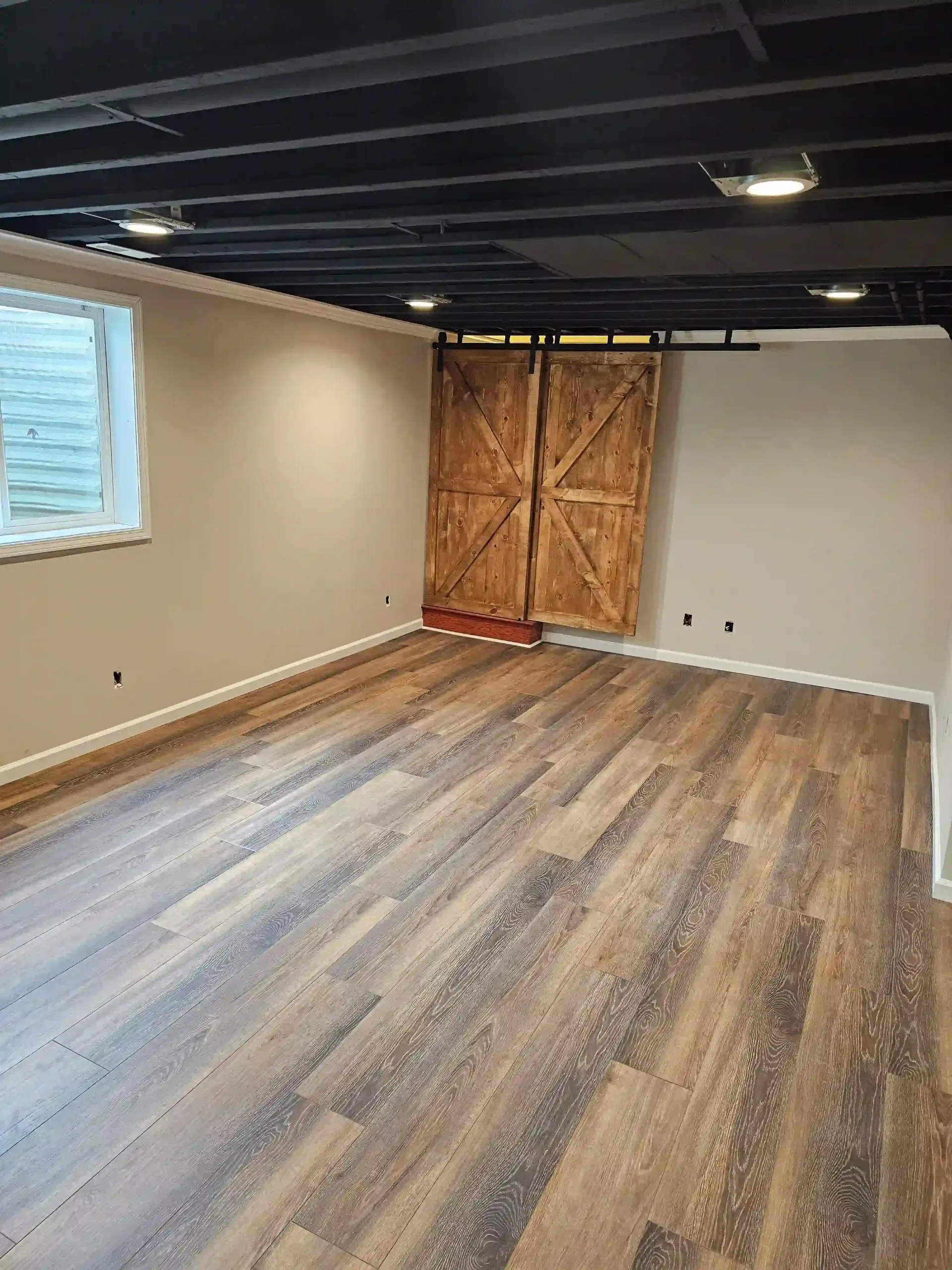 A cozy living space features two cream-colored sofas, a round coffee table, and two white armchairs facing a large window.