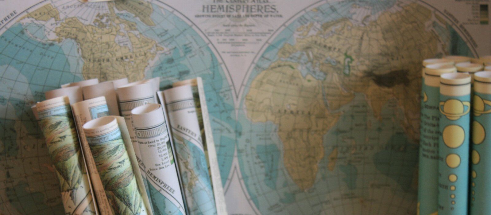 a bunch of maps are sitting on a table in front of a map of the world .