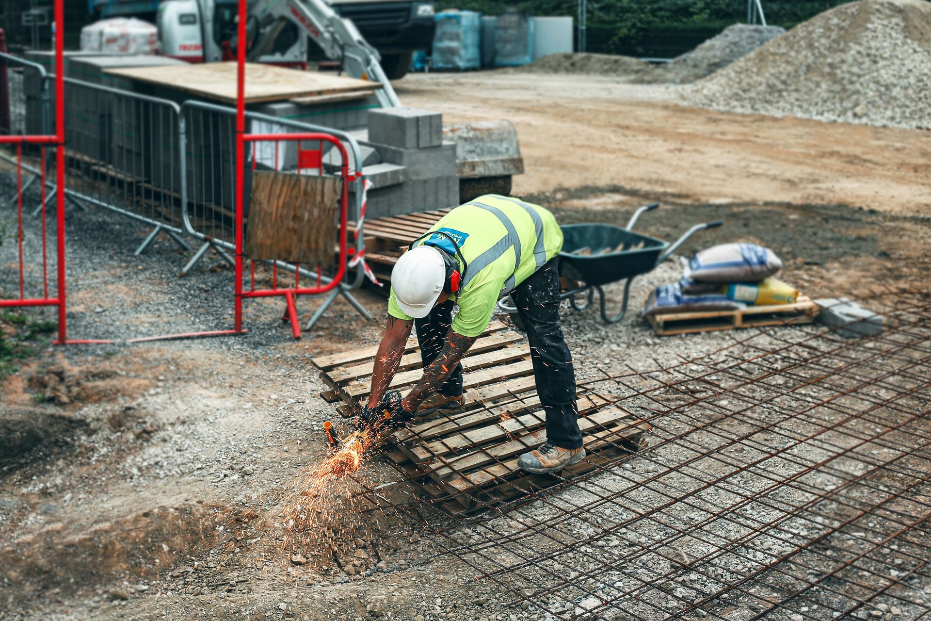 a construction worker is cutting a pallet with a grinder on a construction site .