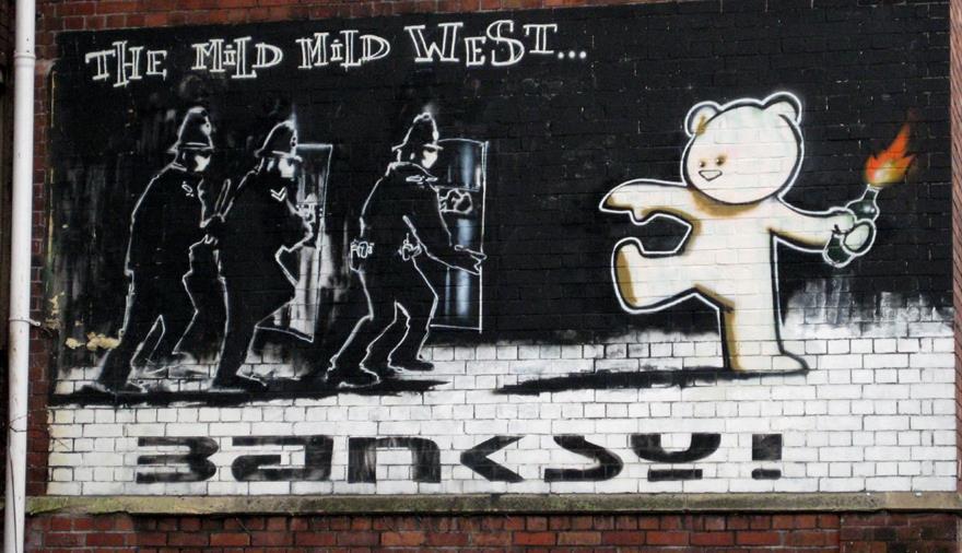 a mural on a brick wall shows a teddy bear holding a torch and the words 