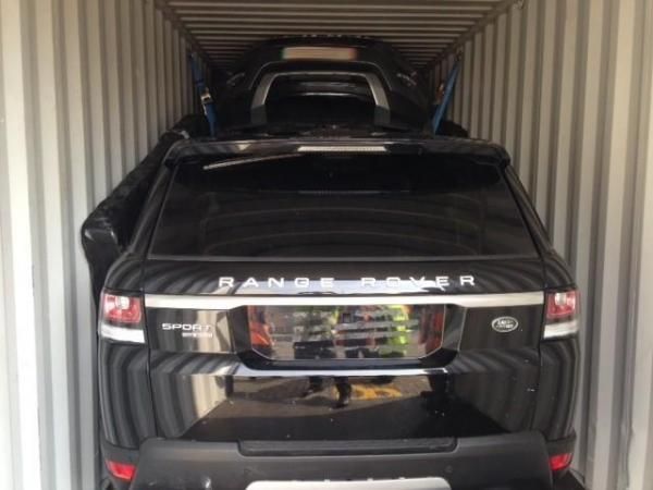 a black range rover is in a shipping container