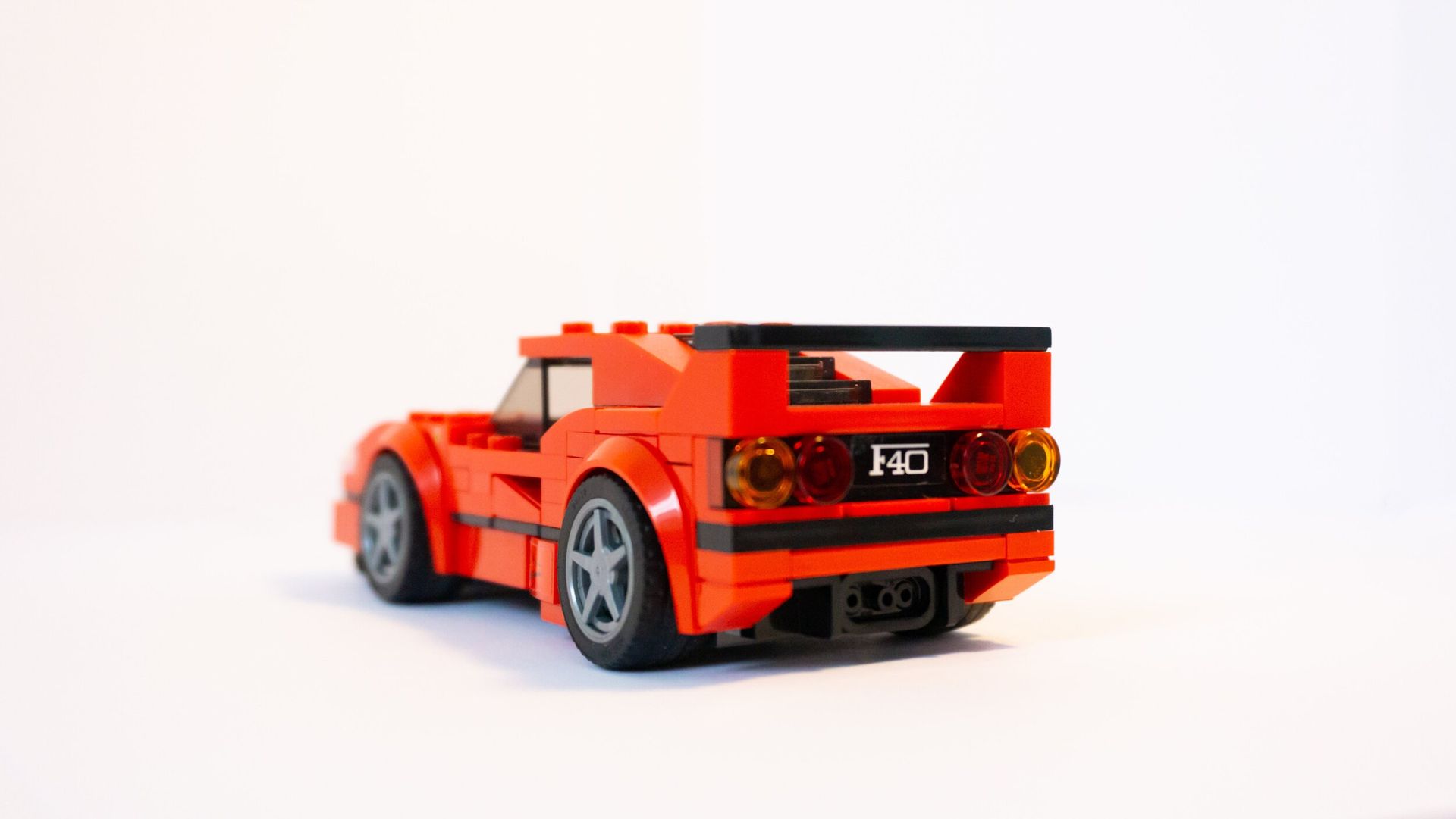 a red lego car is sitting on a white surface .