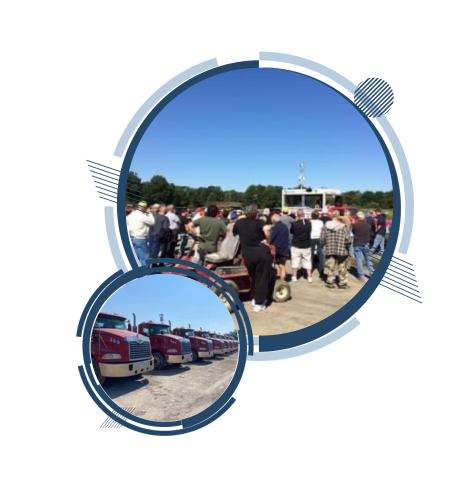 Group of people gathered outdoors; several red semi-trucks parked.