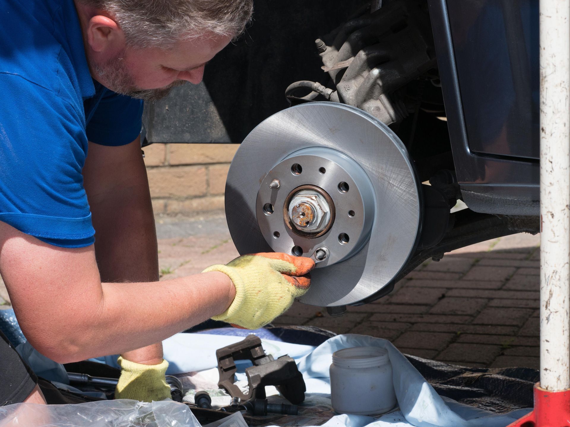 A man is working on a brake disc on a car.
