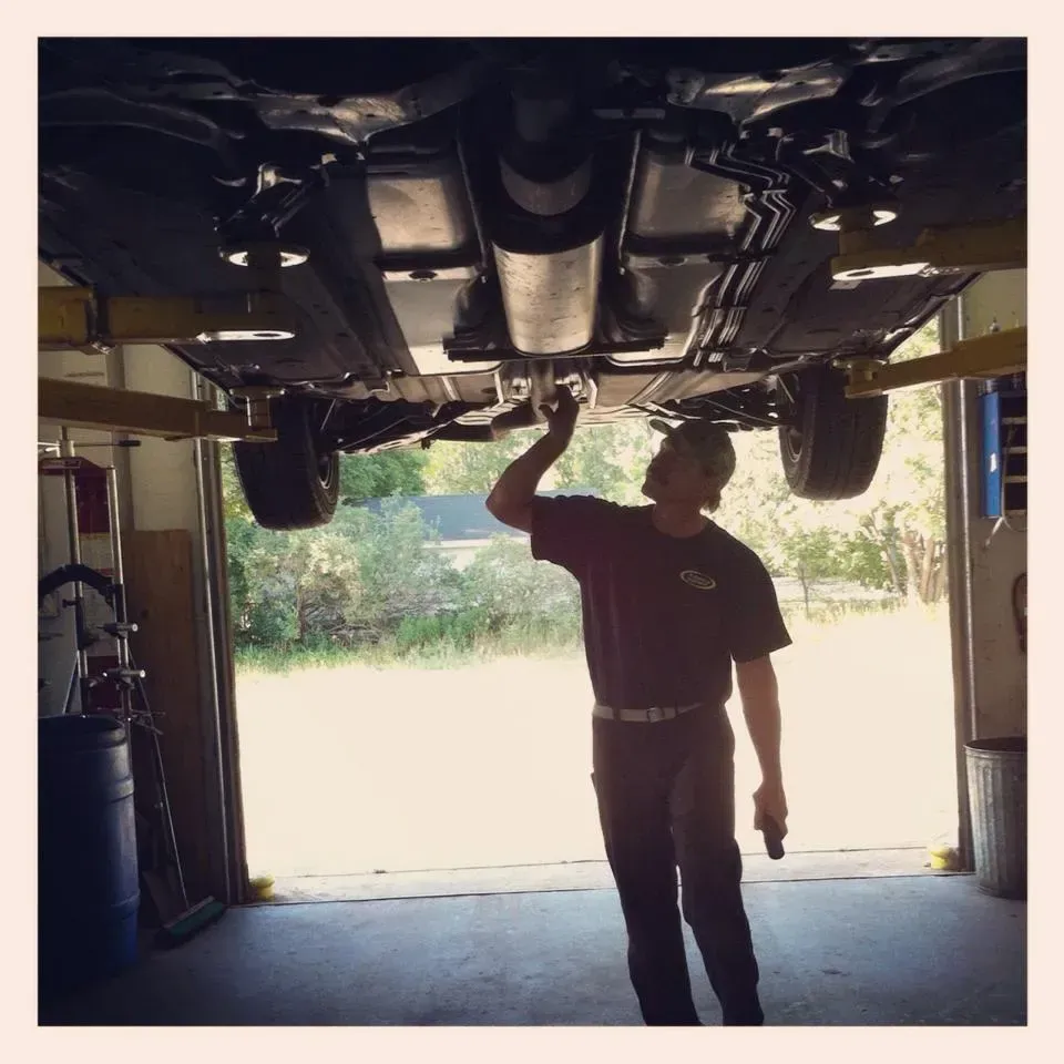 A man is working under a car in a garage