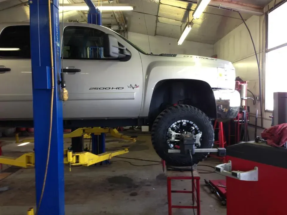 A silver truck is on a lift in a garage