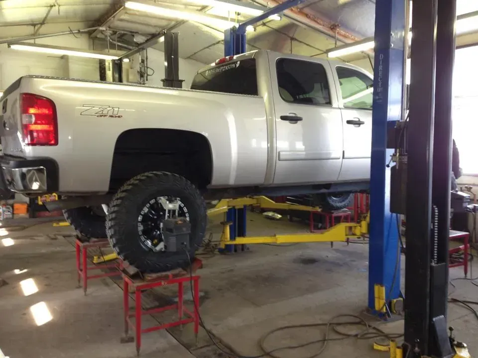 A silver truck is on a lift in a garage