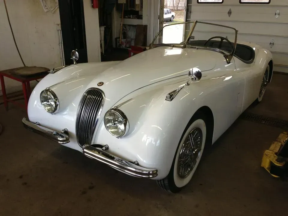 A white jaguar sports car is parked in a garage