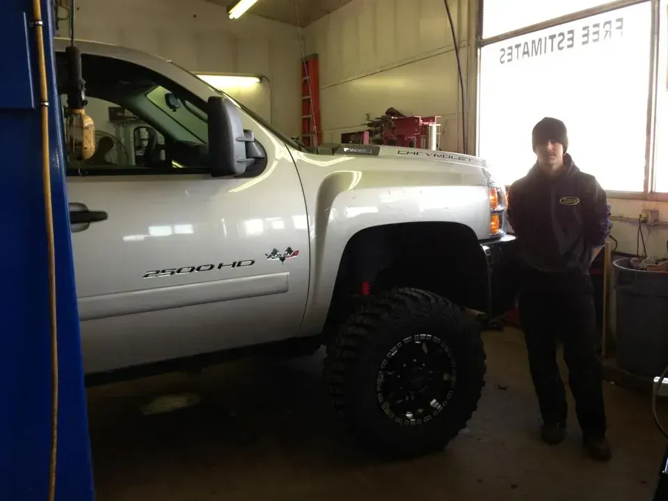 A man is standing next to a white truck in a garage.