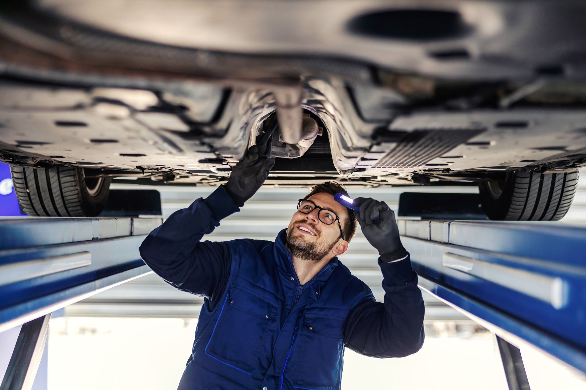A man is working under a car on a lift.