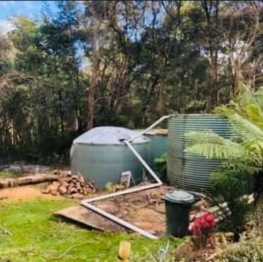 A large water tank is sitting in the middle of a lush green field.