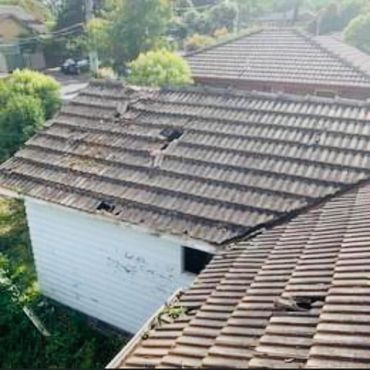 An aerial view of a house with a broken tile roof.