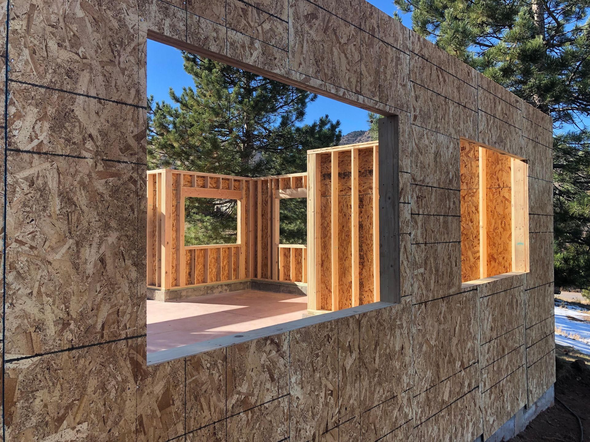 Partially built house with a stone exterior and open wooden window frames under construction