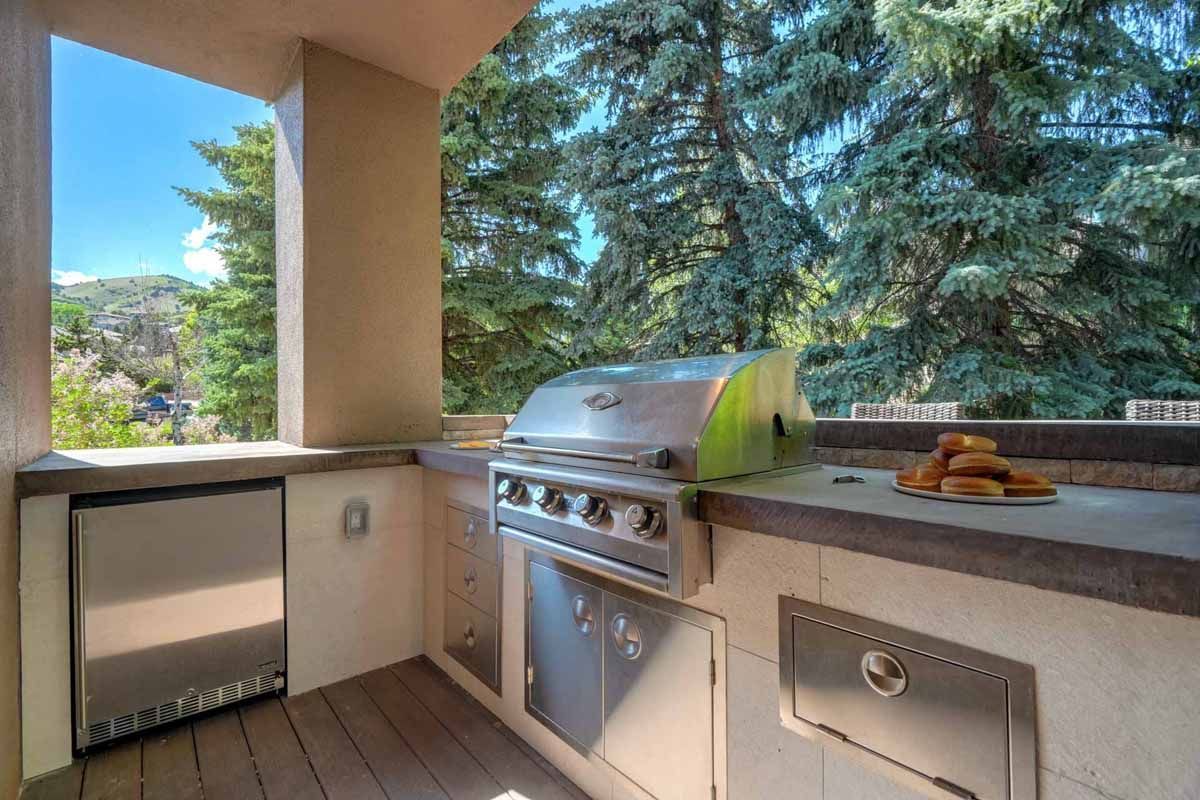 Outdoor patio kitchen with stainless grill, countertop, and mountains beyond